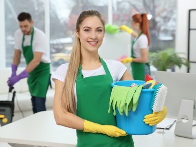 Young female worker holding cleaning supplies at office Young female worker holding cleaning supplies at office